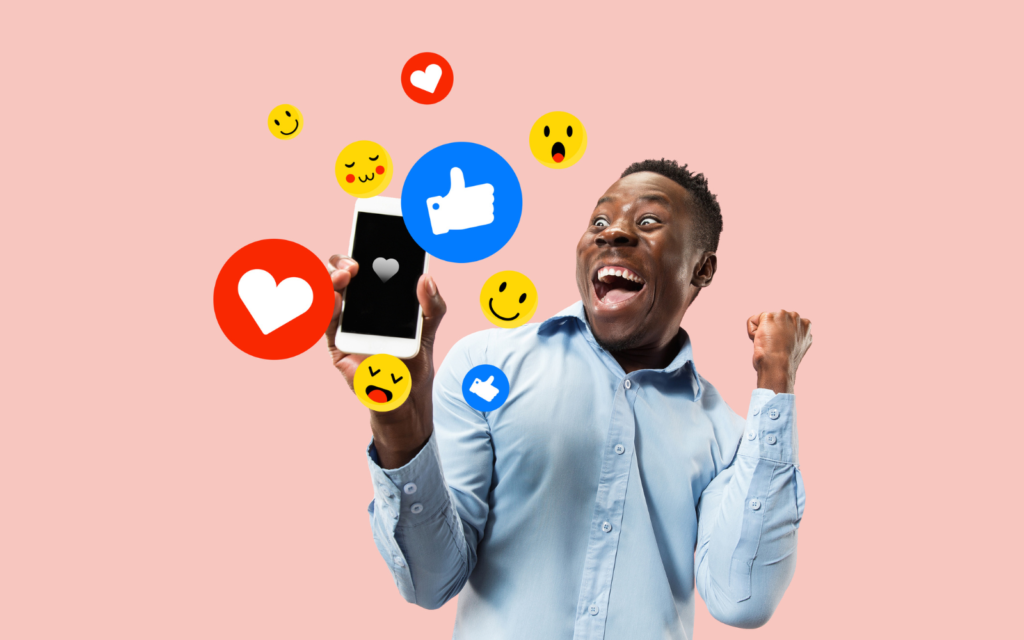  Excited man holding a smartphone as social media reaction icons float around him