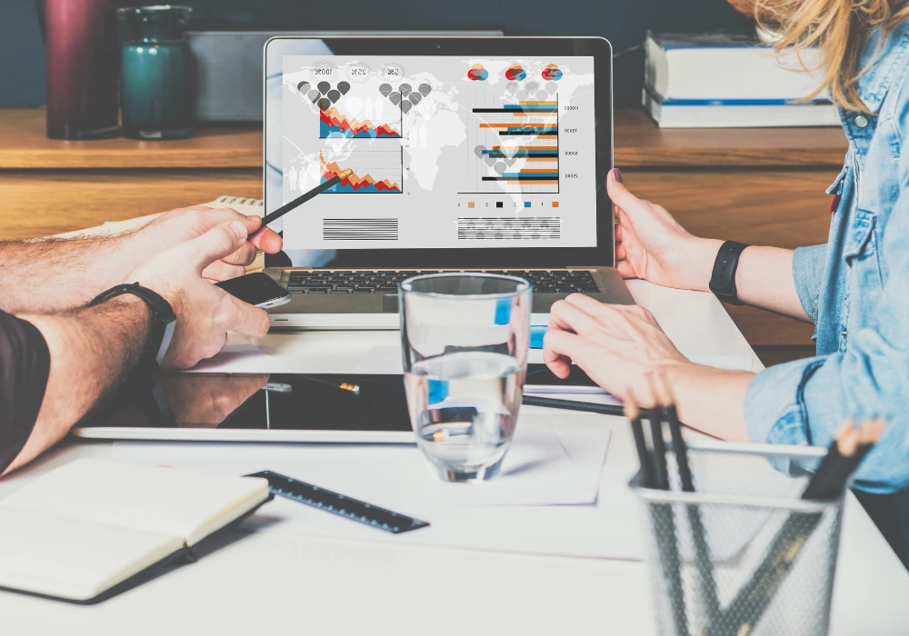 Two people analyzing SEO and PPC data on a laptop screen