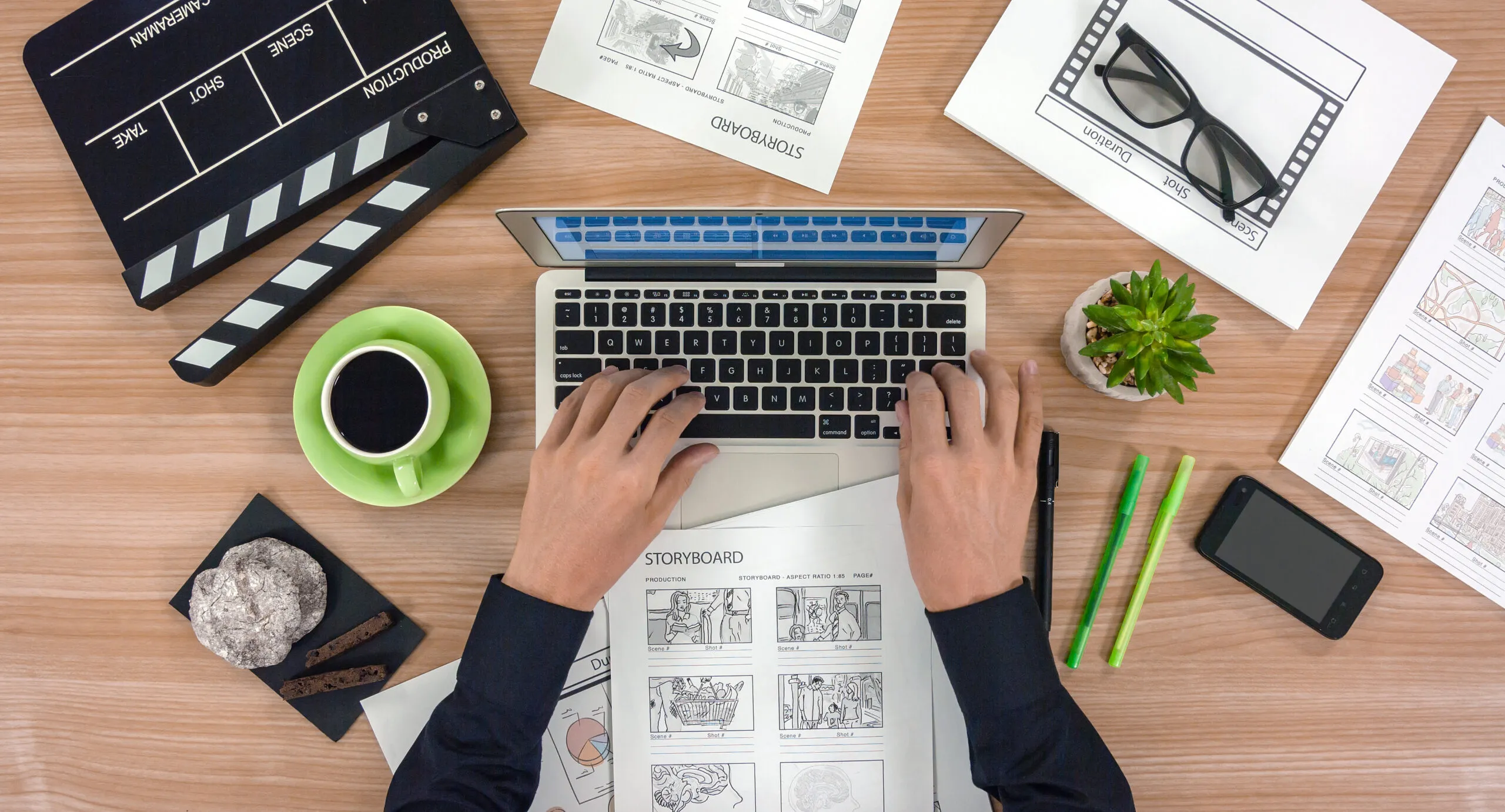 a female working on video script storyboard, using laptop, cup of black coffee on table